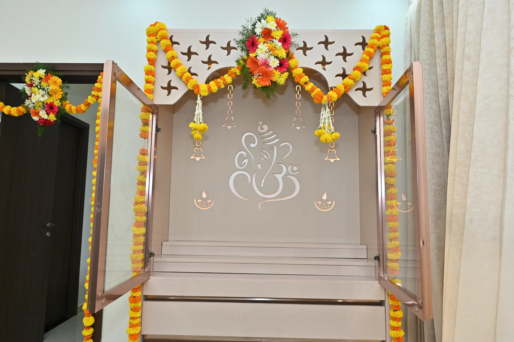 Custom backlit Ganesha puja unit with glass doors designed by Nook & Kove in Bengaluru
